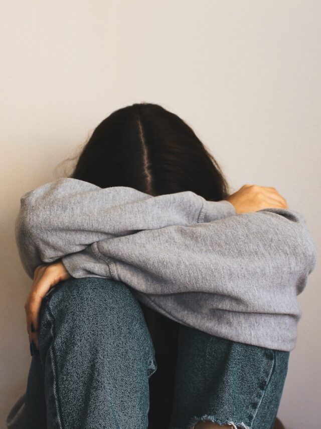 What is PCOS? a woman sitting on the floor with her arms wrapped around her head