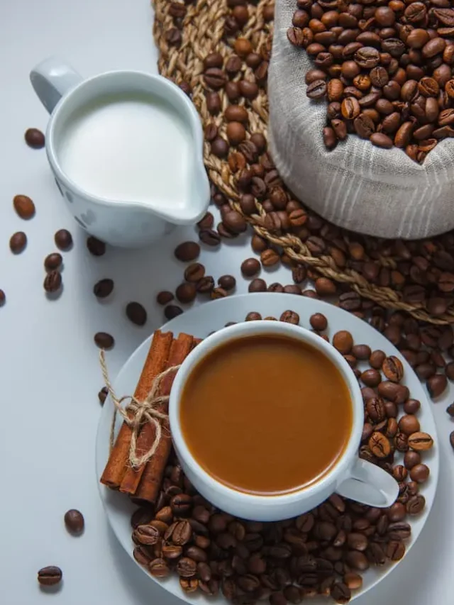 cup-coffee-with-coffee-beans-sack-saucer-milk-dry-cinnamon-high-angle-view-trivet-white-surface (1)